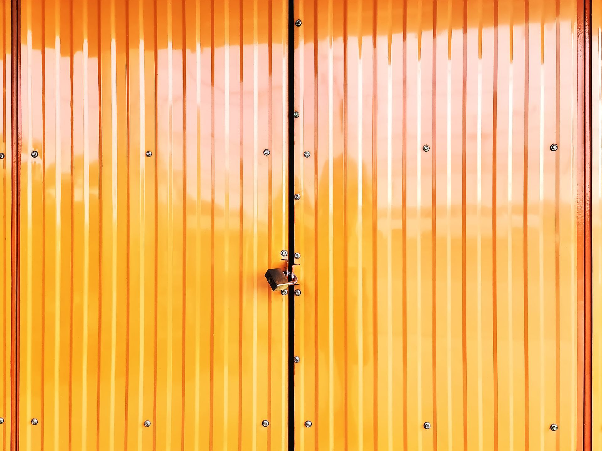 Orange corrugated metal double doors, padlocked shut.