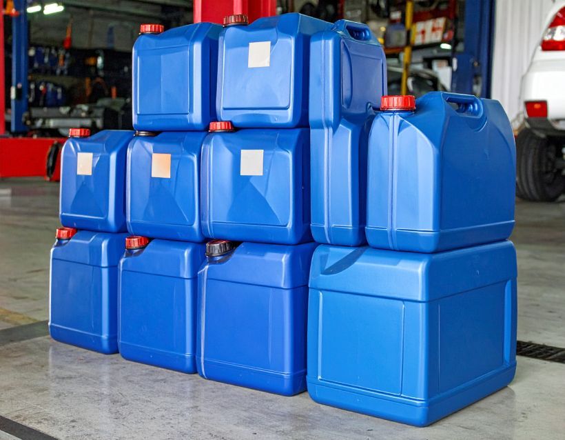 Blue plastic containers stacked in a garage setting with a car in the background.