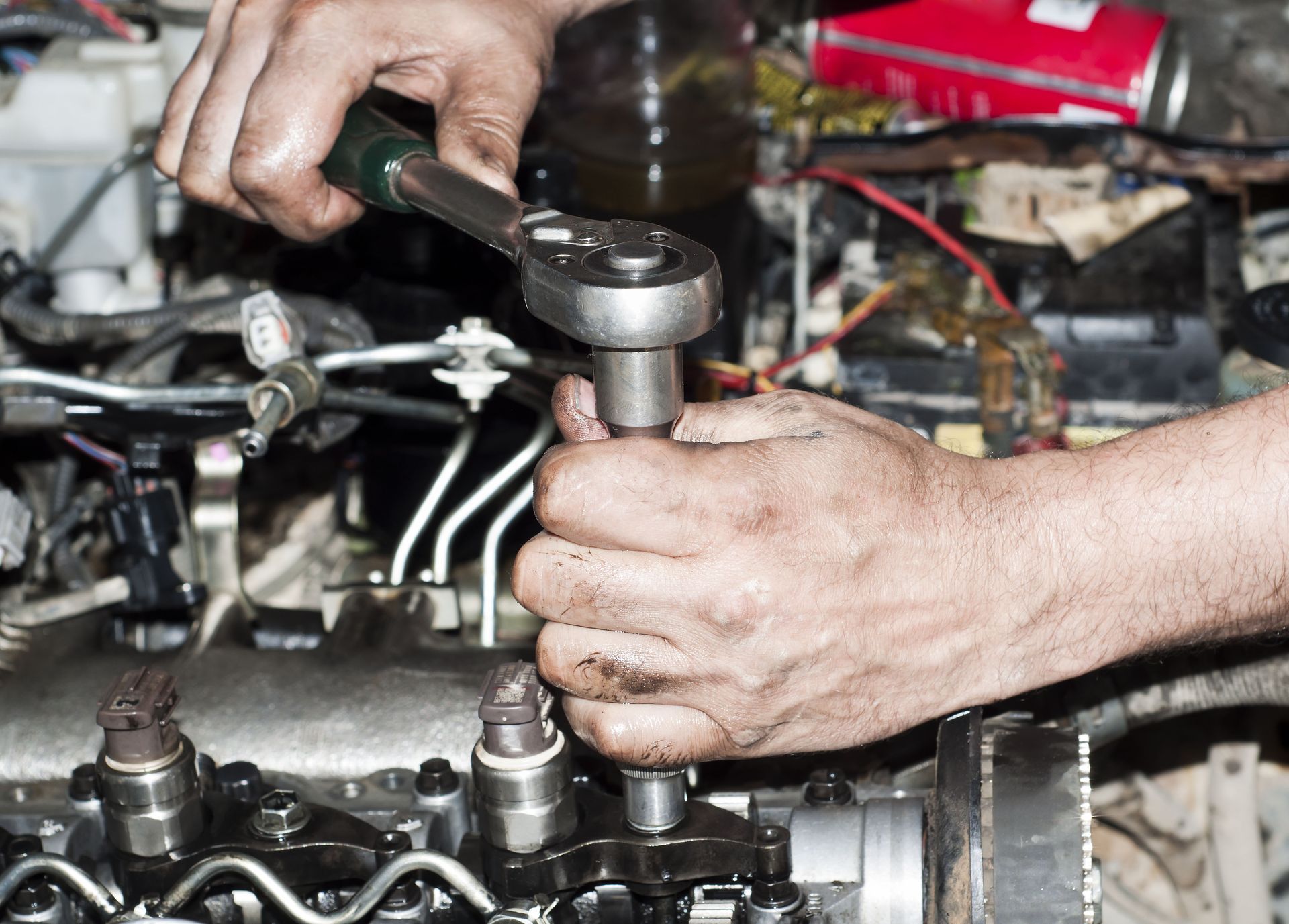 A man is working on a car engine with a wrench.