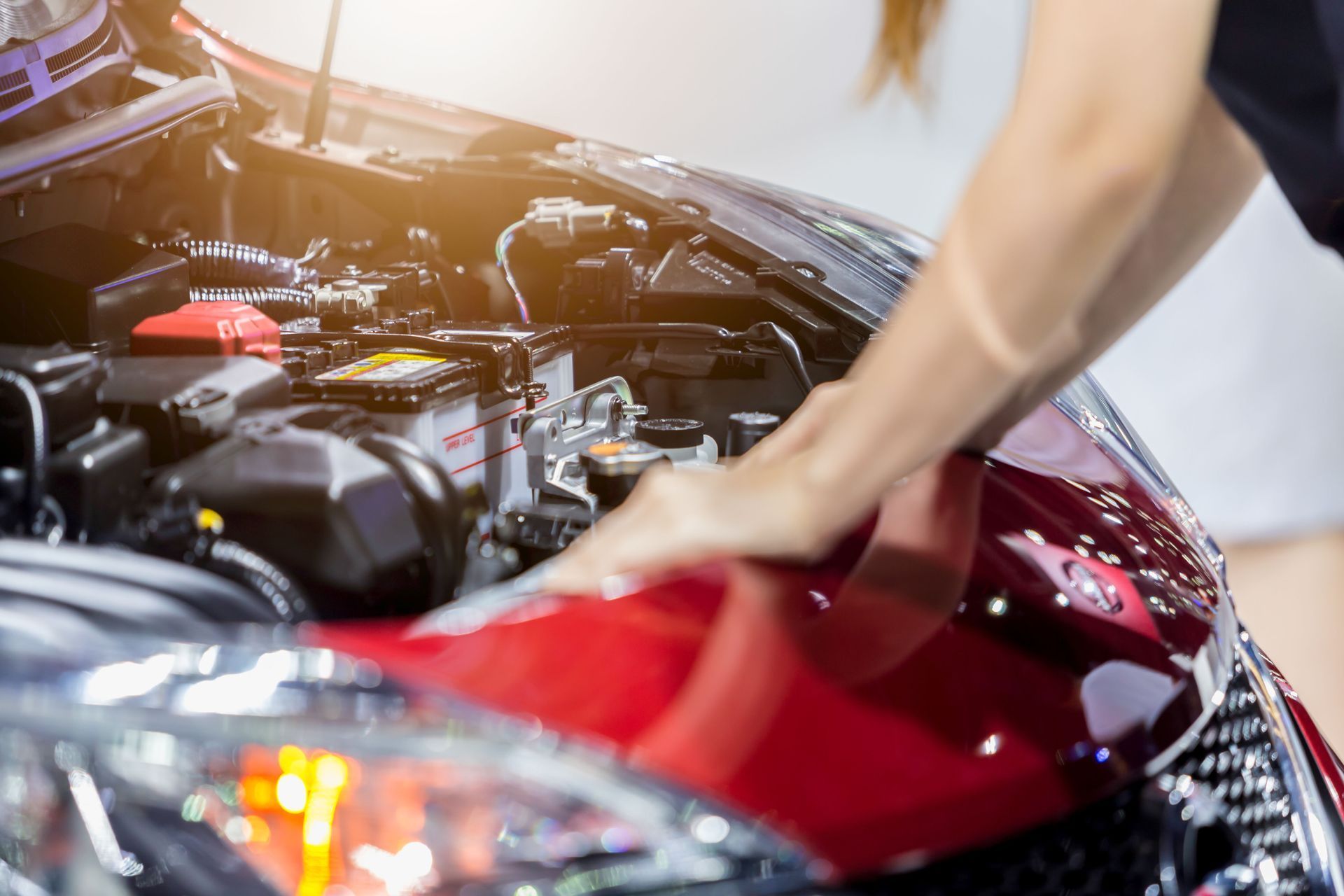 A woman is cleaning the hood of a red car.