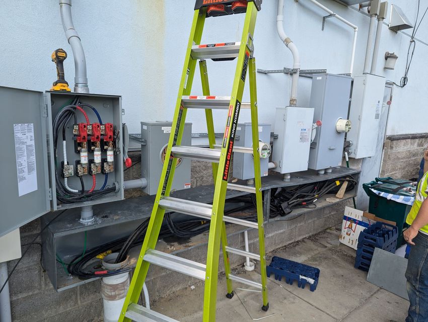A man is standing next to a ladder in front of a building.