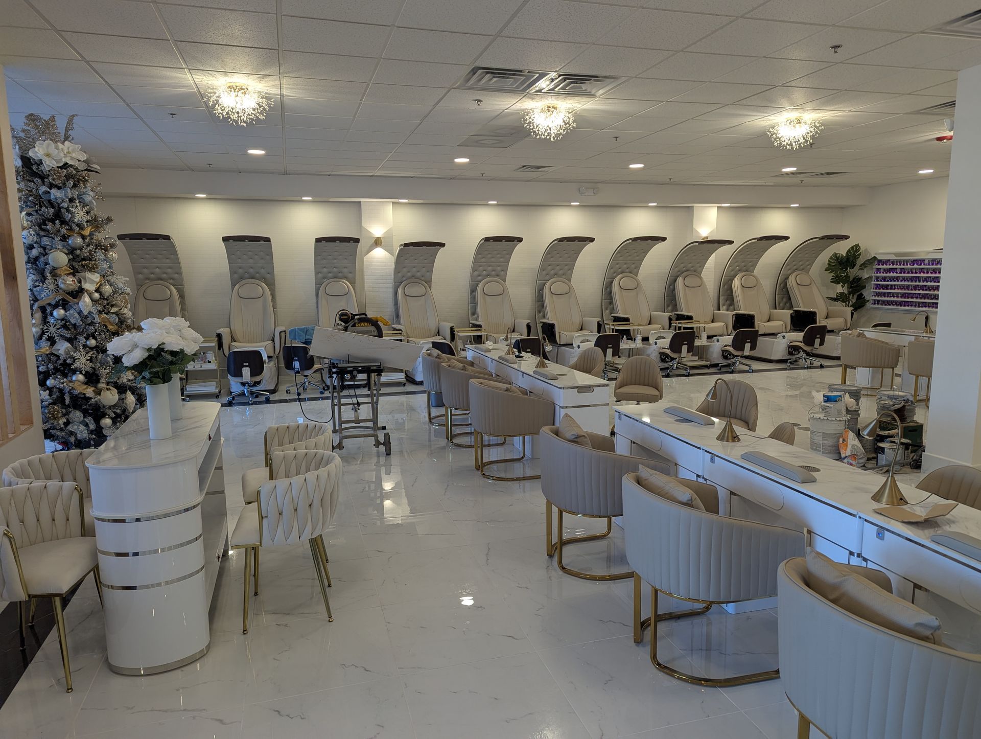 A large room with a lot of chairs and tables in a nail salon.