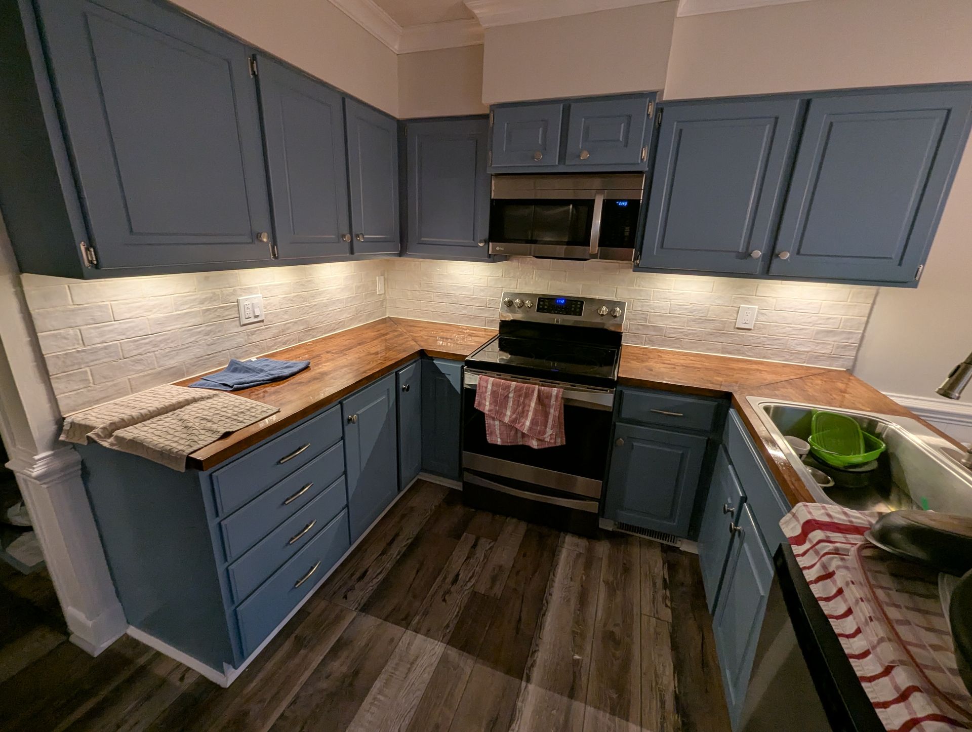 A kitchen with blue cabinets , a stove , and a sink.