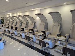 A row of chairs are lined up in a nail salon.