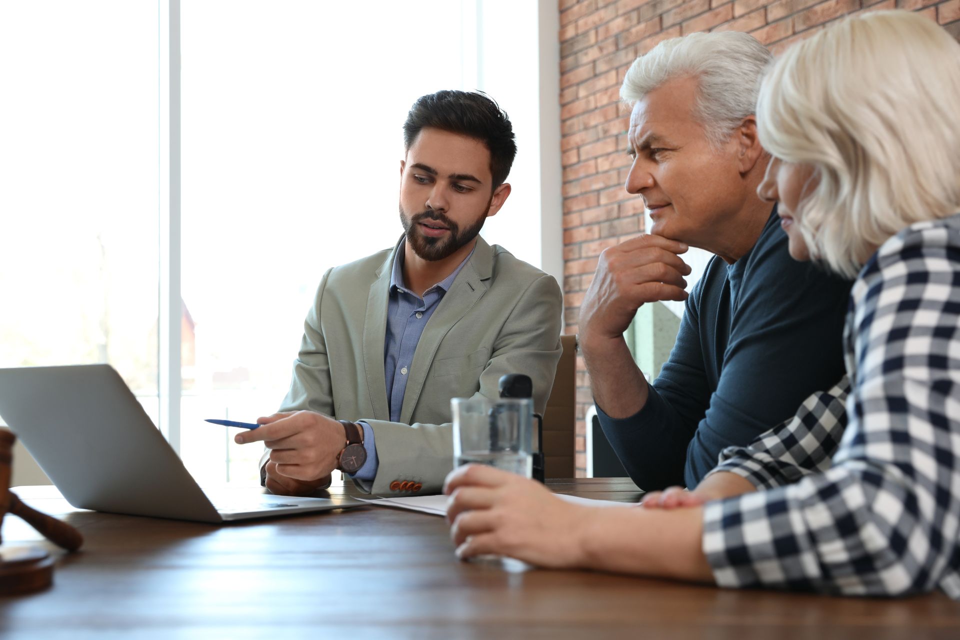 Three colleagues discussing work at a table with a laptop and documents in an office