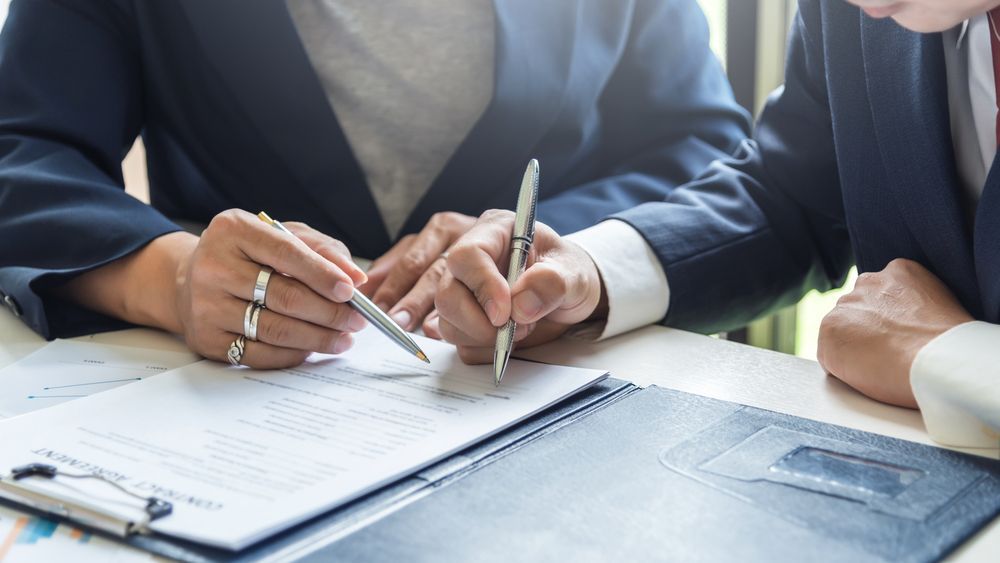 Two people are sitting at a table signing a document.