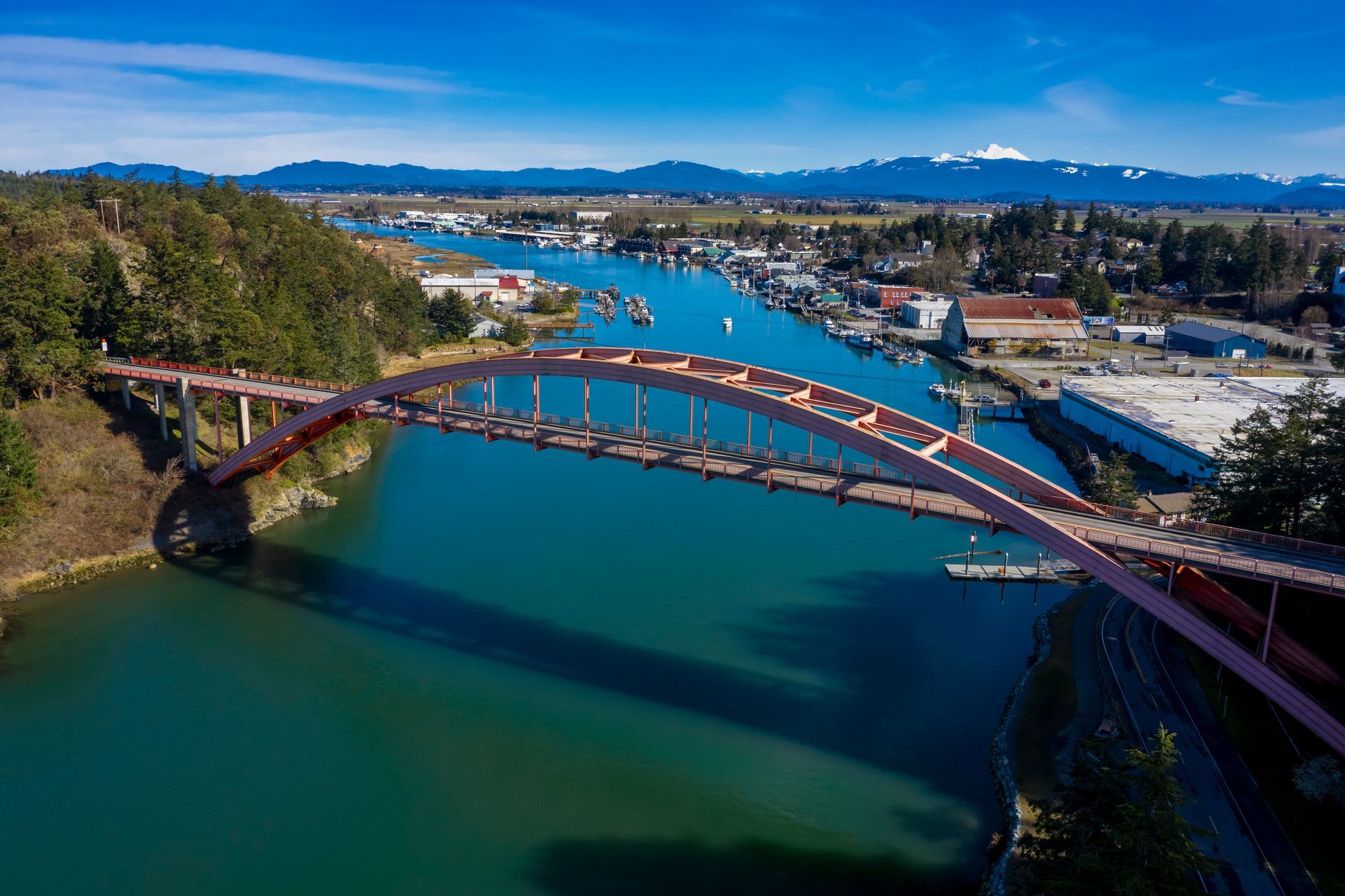 An aerial view of a bridge over a river with mountains in the background.