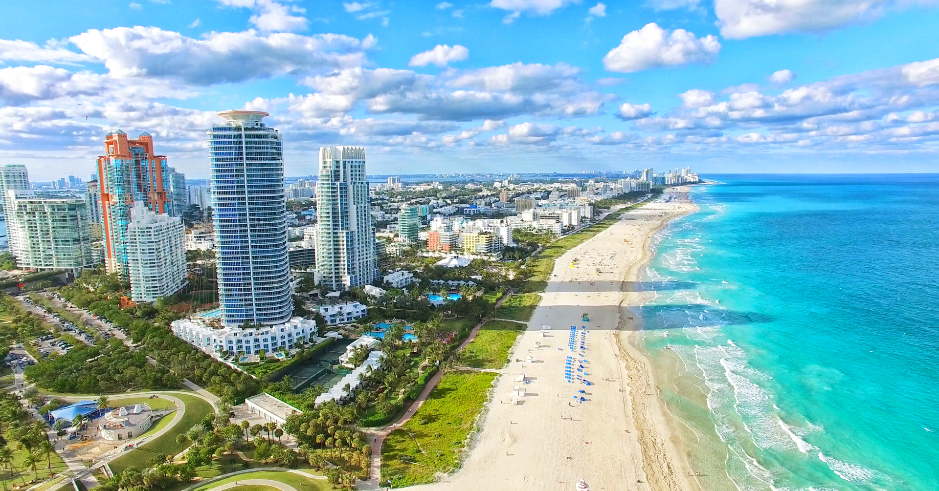An aerial view of a beach in miami with a city in the background.