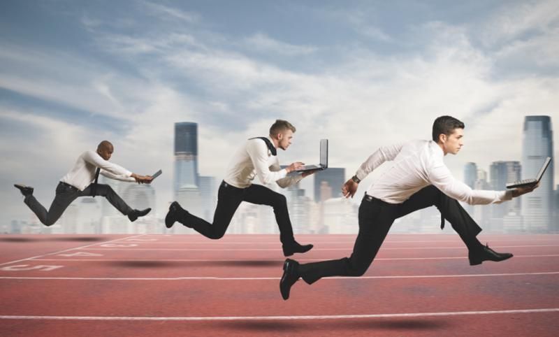 Three businessmen are running on a track with laptops.