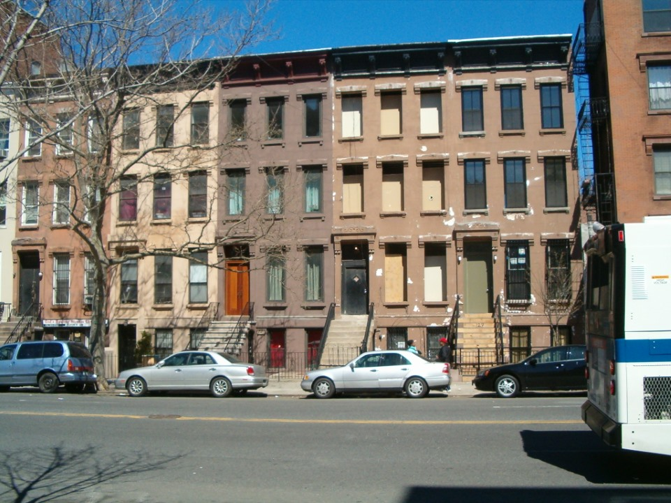A large house with a porch and a large lawn in front of it.