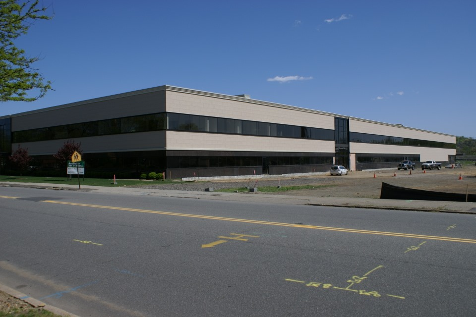 A row of cars are parked in front of a red building.