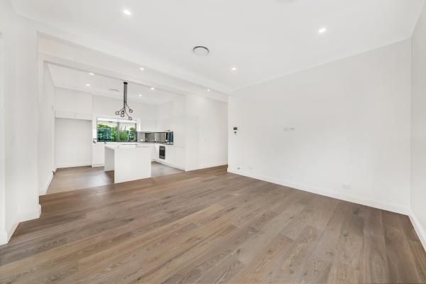 An Empty Living Room with Hardwood Floors and A Kitchen in The Background | Mid-North Coast, NSW | BDM Constructions