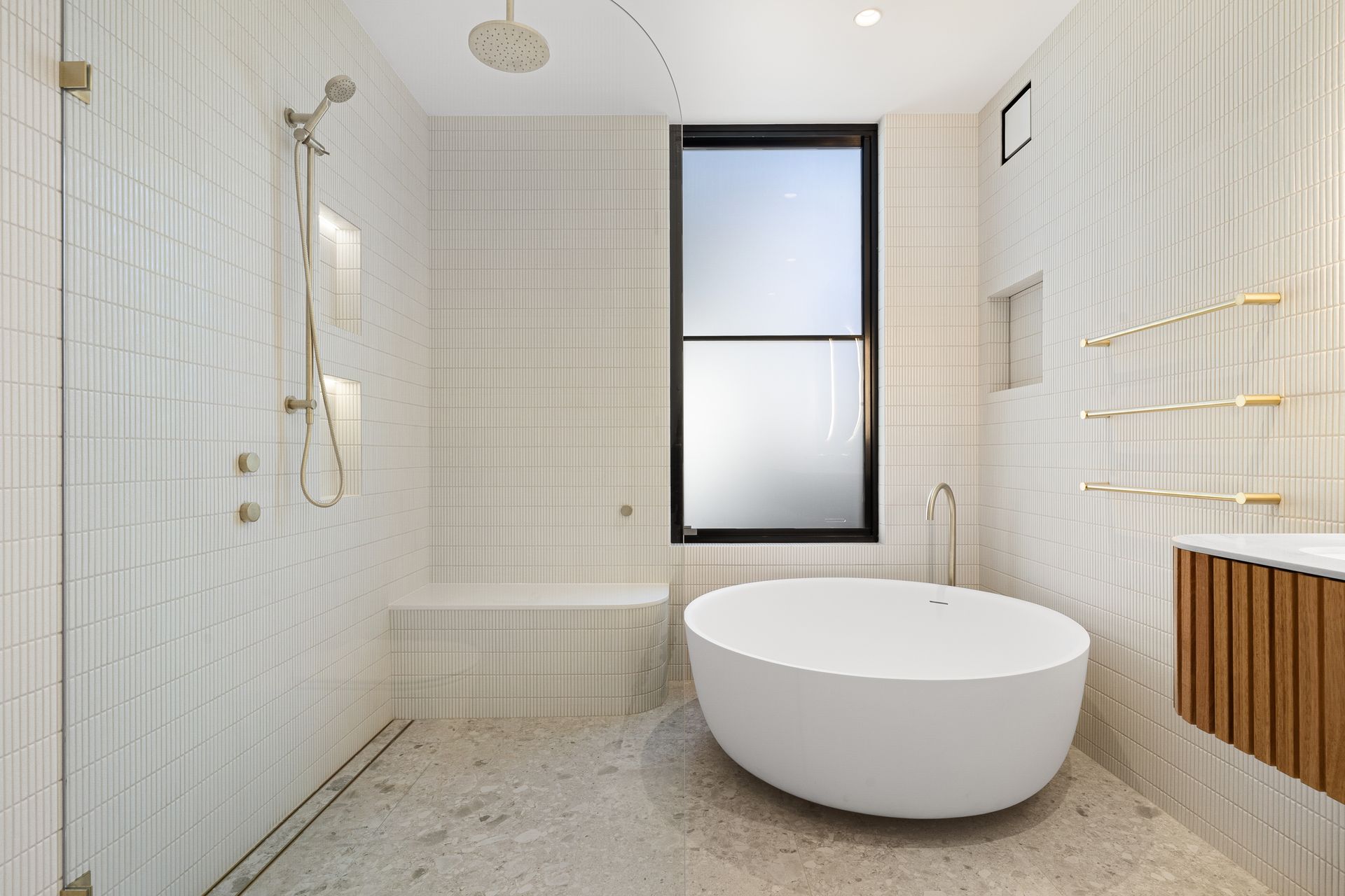 A bathroom with a tub , shower , sink and window.
