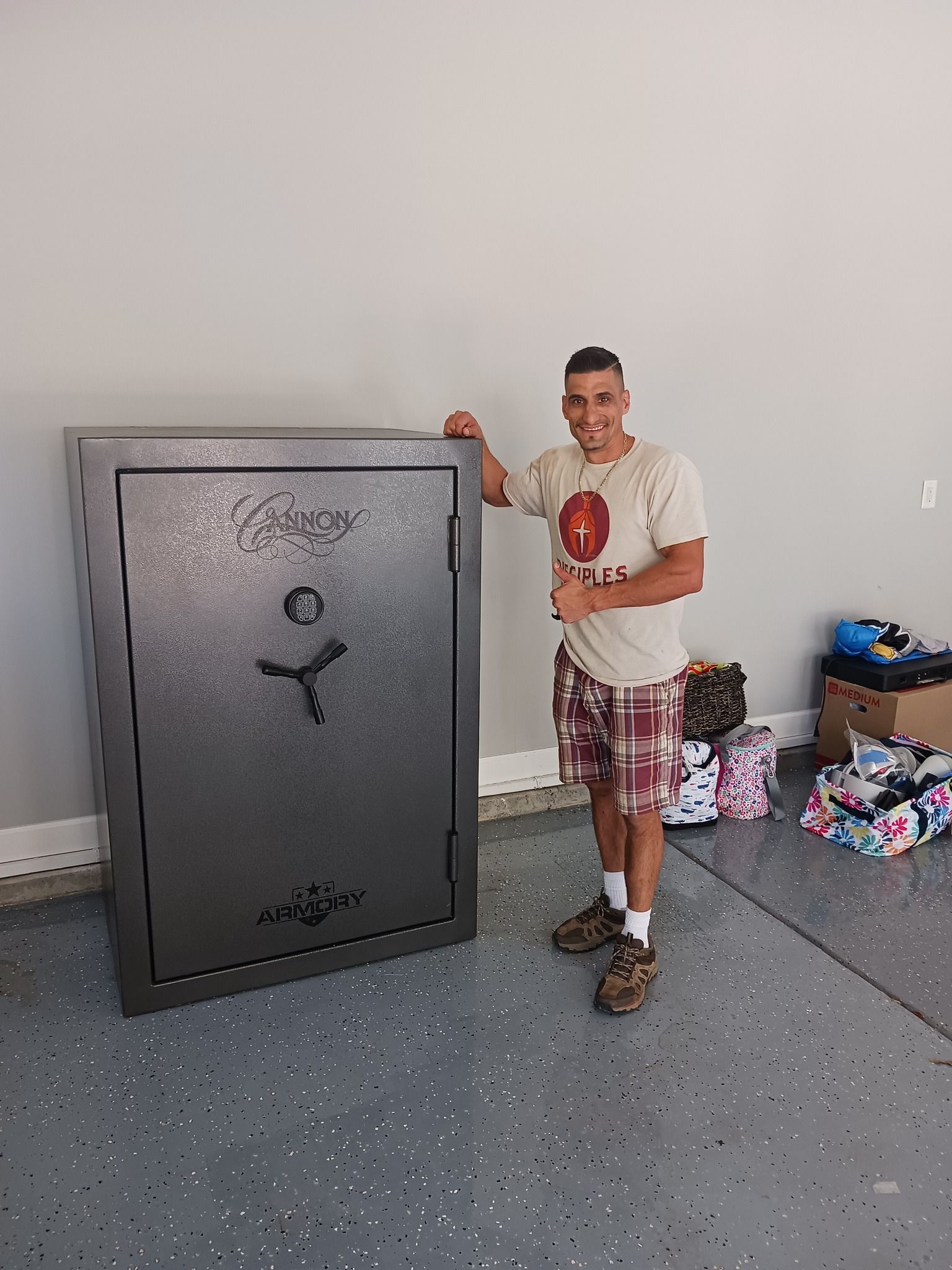 A man is standing next to a large safe in a garage.