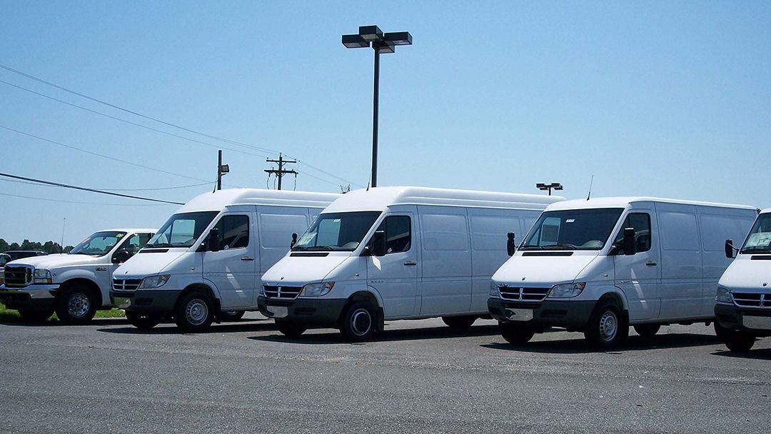 White cargo vans parked outdoors on a sunny day.