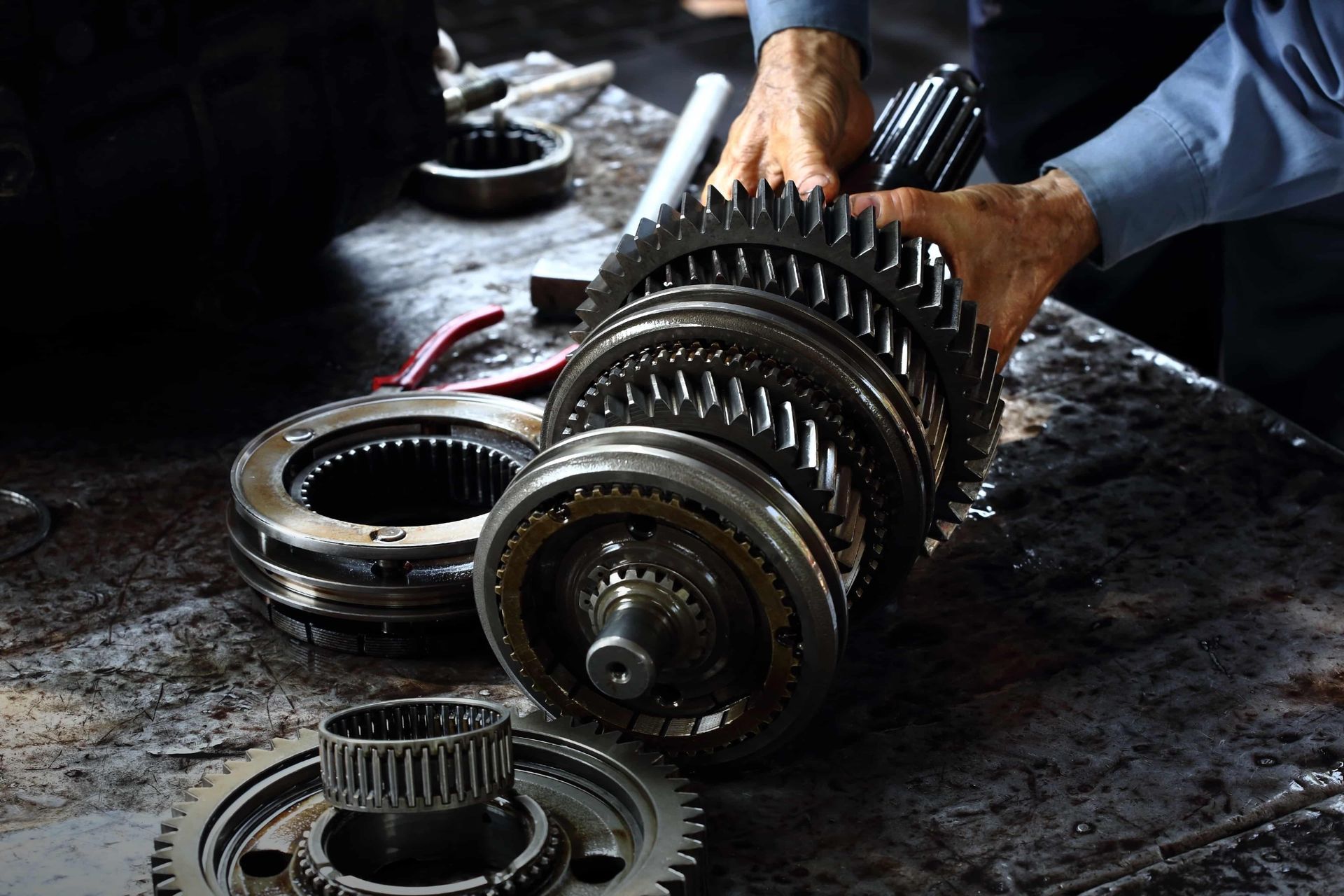 A man is working on a pile of gears on the floor.