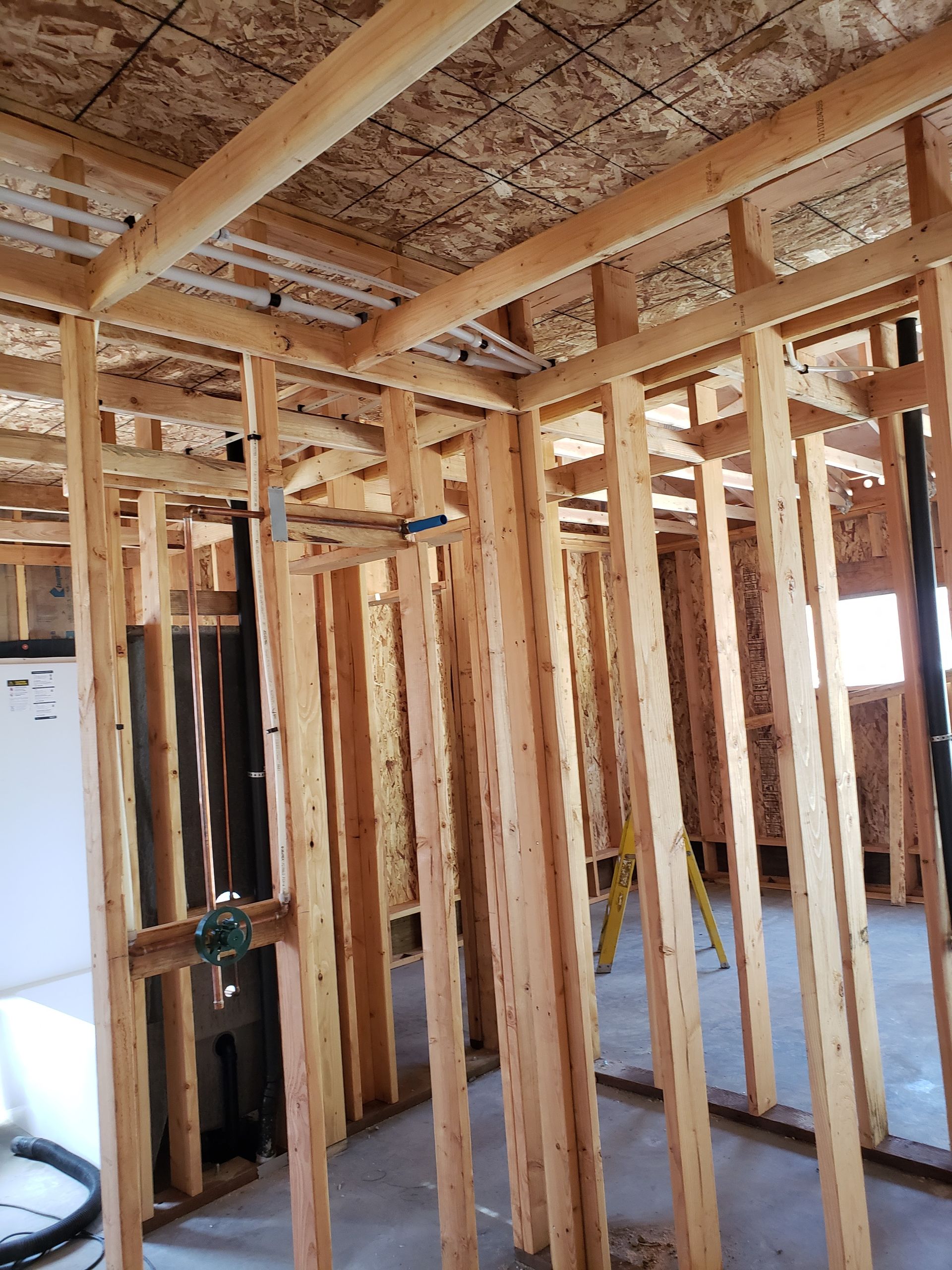 Framed interior of a house under construction with exposed wood studs and ceiling joists