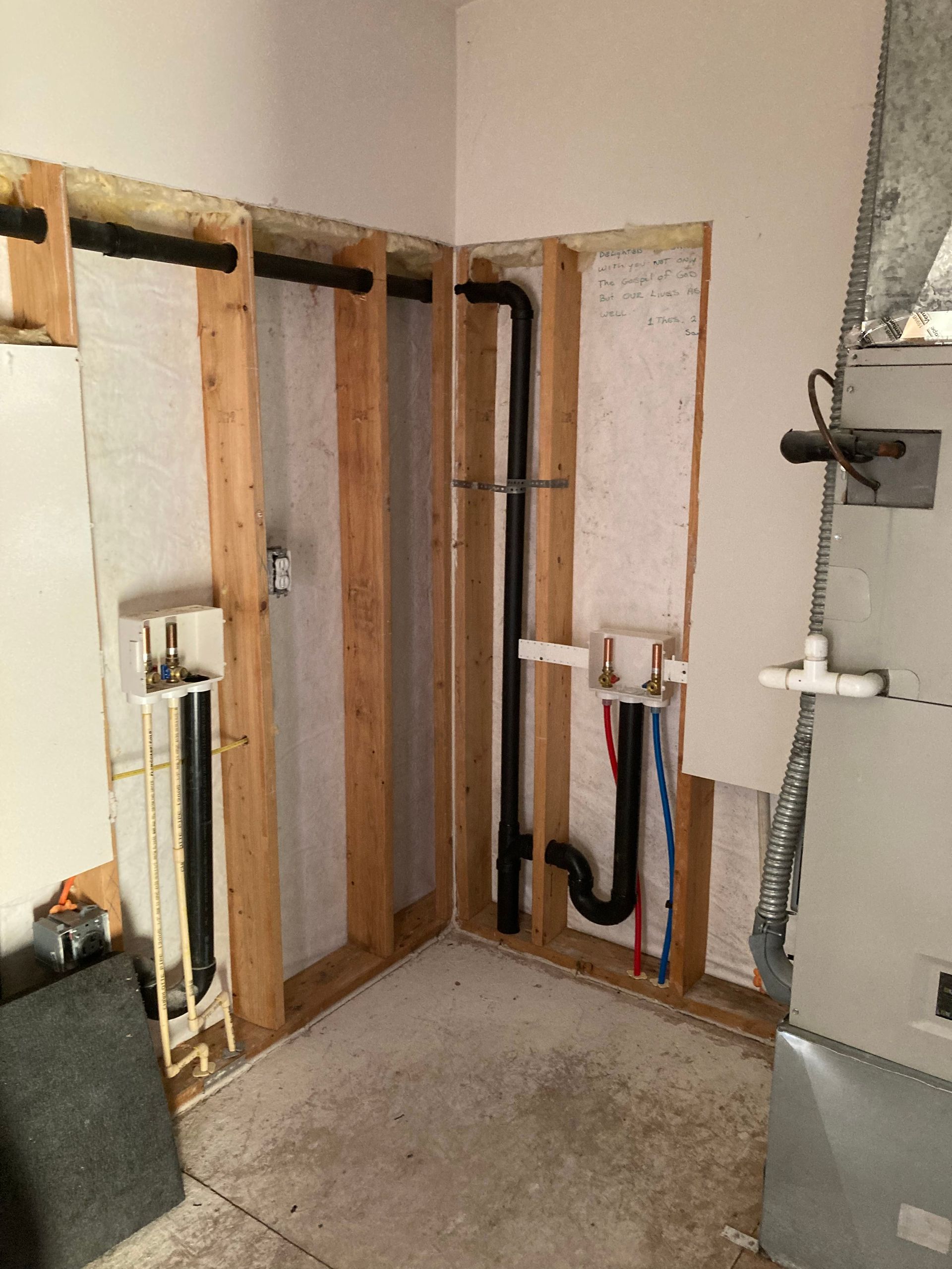 Partially gutted room with exposed wall framing, plumbing, and concrete floor during renovation