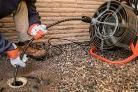 Person in a hose down area next to a large fan, with coiled hoses and debris on the ground.