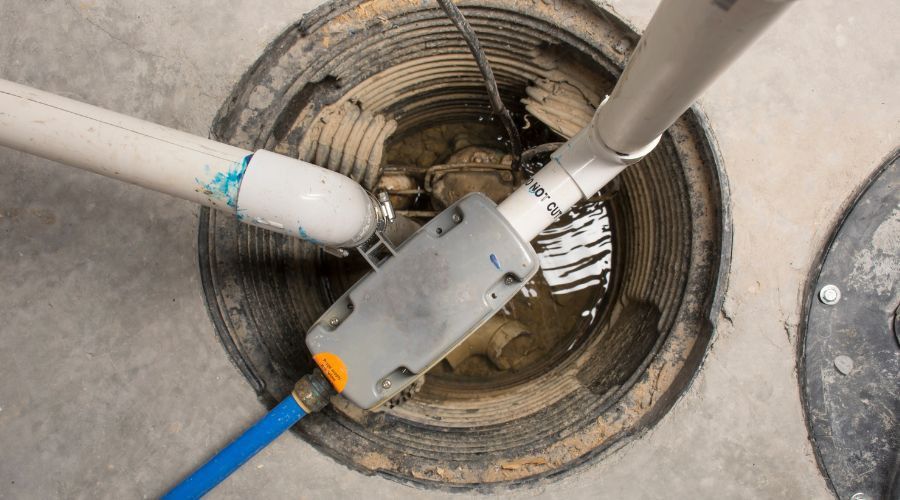 Blue cable connected to a gray device lowered into a circular concrete manhole opening