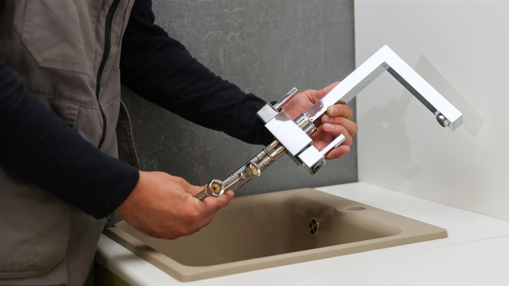 Hands using a portable faucet attachment over a sink basin