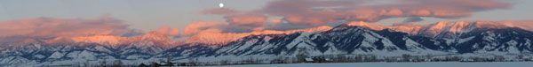 Mountains under a pink and orange sunset. A small, bright dot is above the peaks.