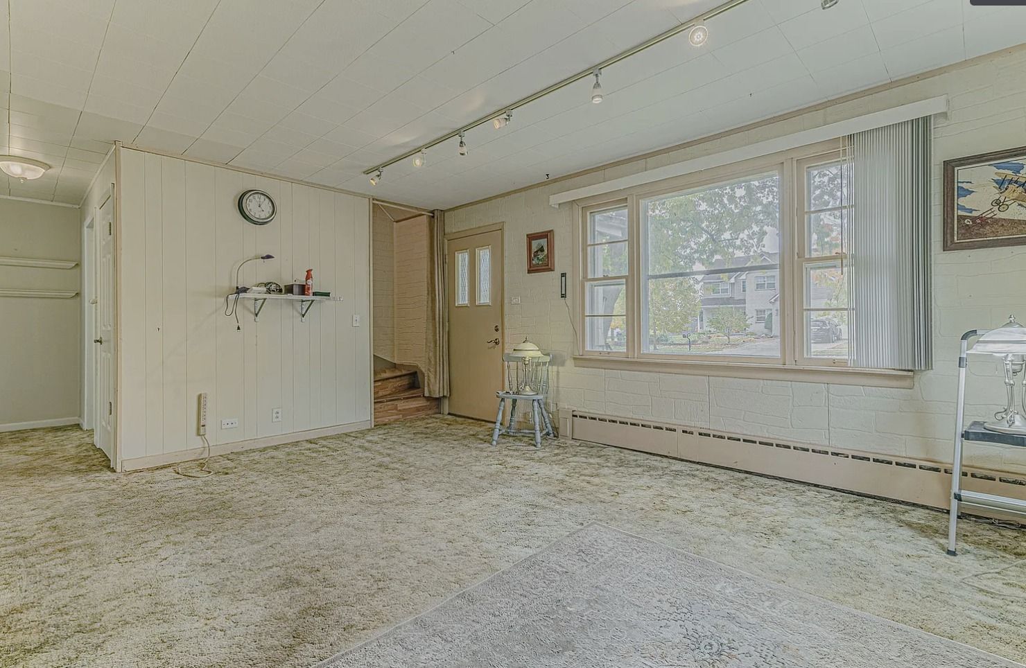 Empty room with white walls, window, door, and shag carpet.