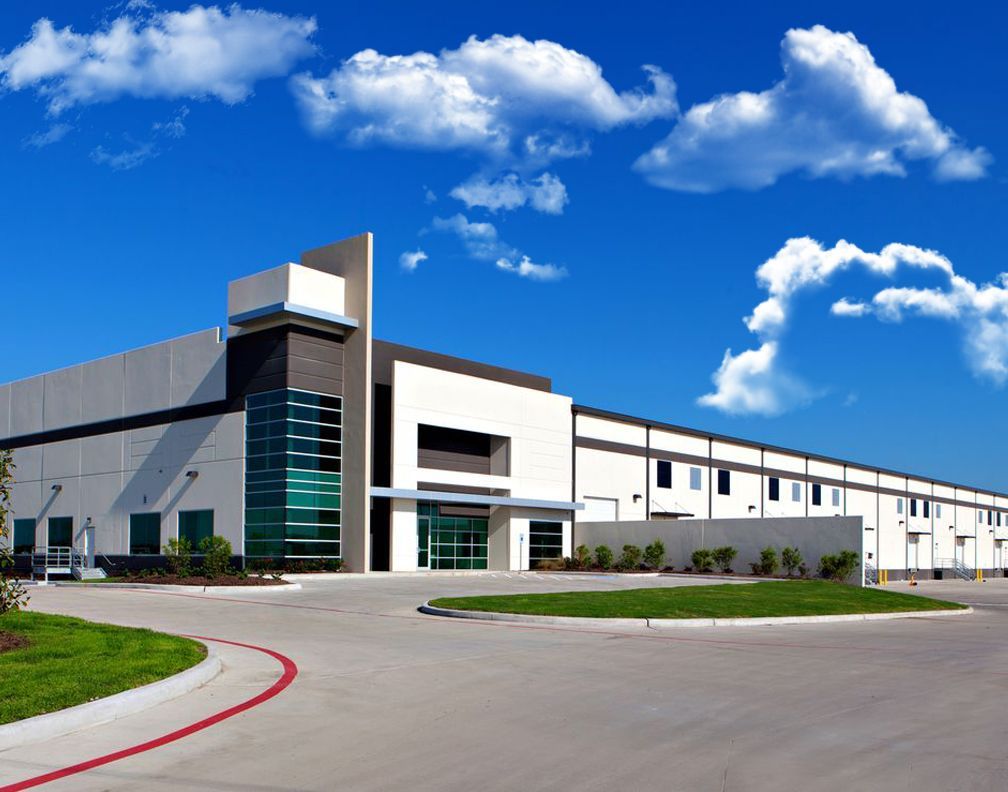 Electrician in a safety vest and hard hat inspects electrical panel.