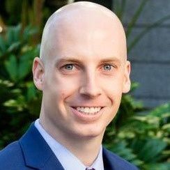 A bald man in a suit and tie is smiling for the camera.