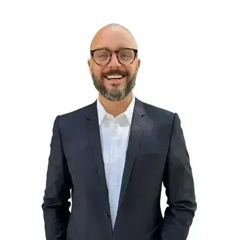A man in a suit and tie is standing in front of a plant.