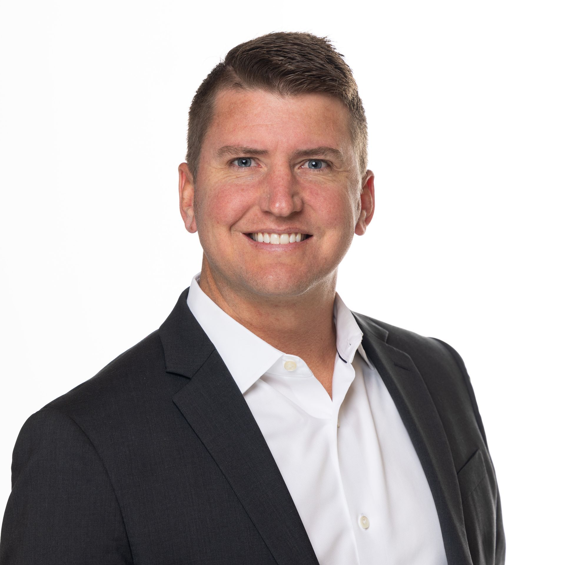 A man in a suit and white shirt is smiling for the camera.