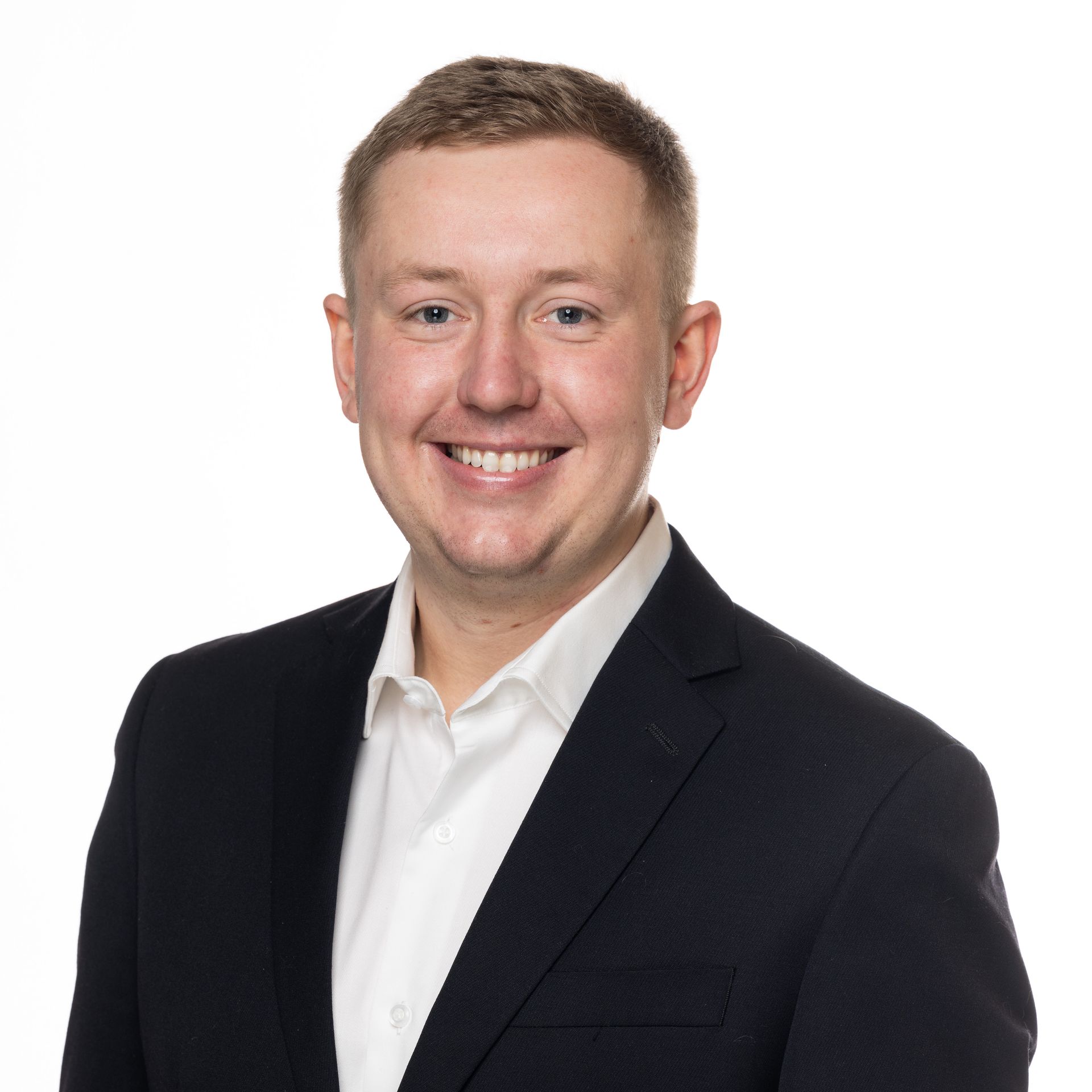 A man in a suit and white shirt is smiling for the camera