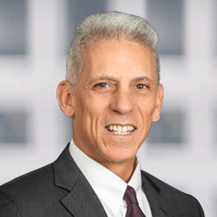 A bald man in a suit and tie is smiling for the camera.