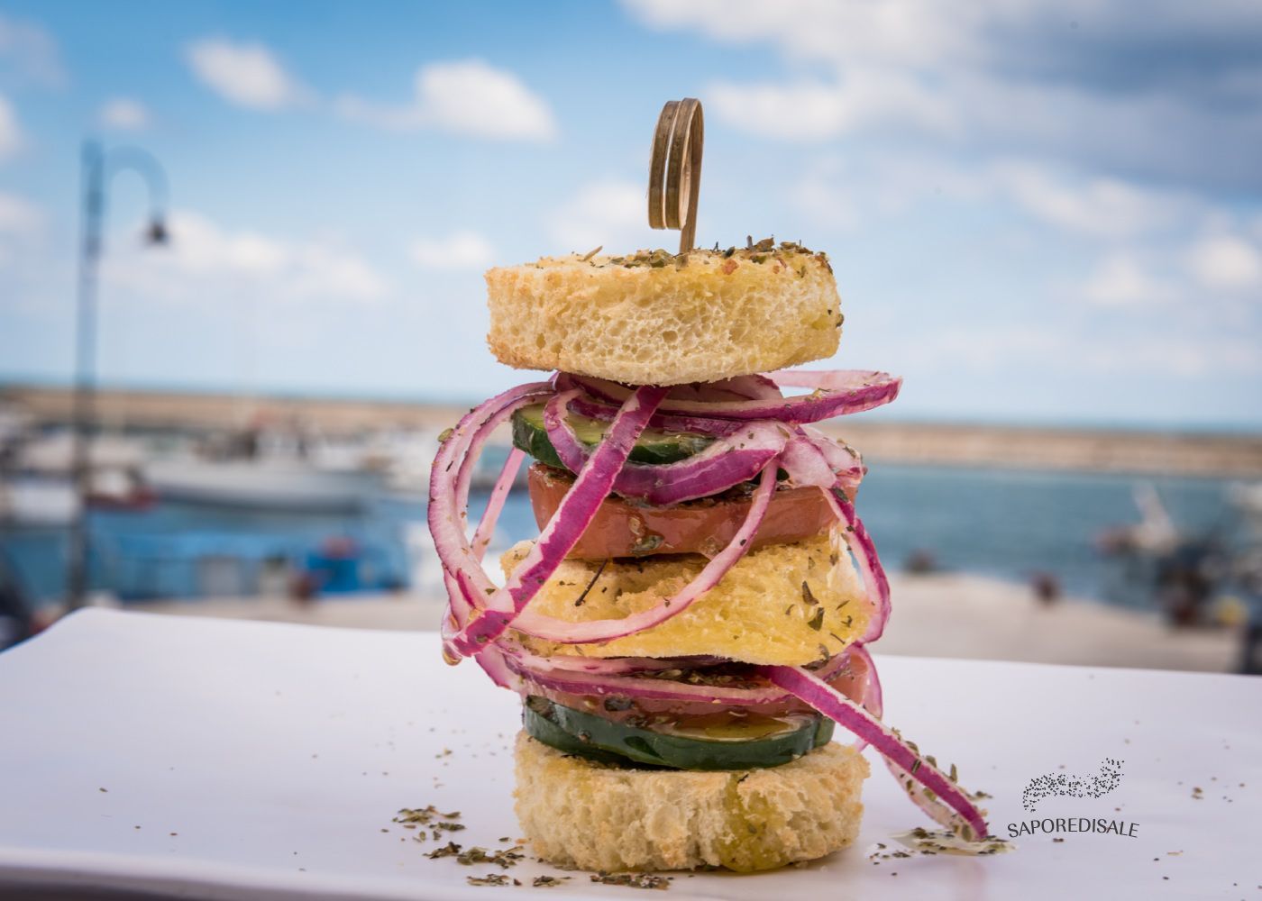 Antipasto composto da pane, cipolla rossa e cetriolo, tenuti insieme da uno spiedino.