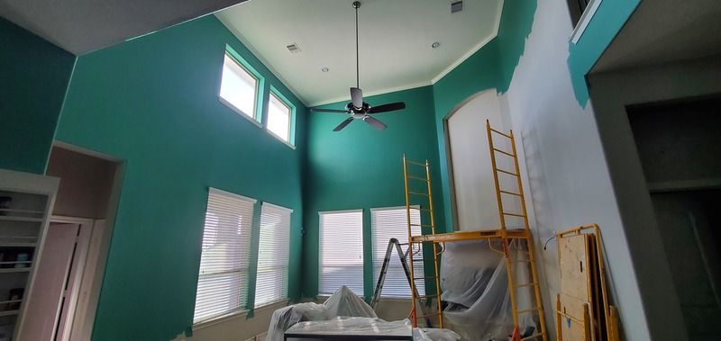 A living room with green walls and a ceiling fan.