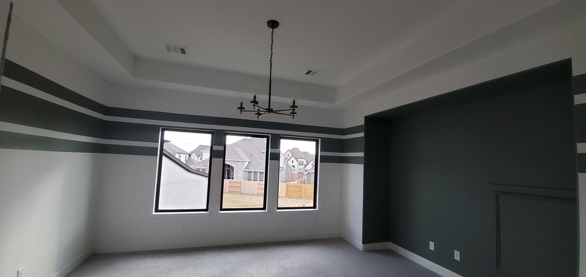 An empty room with a chandelier hanging from the ceiling.