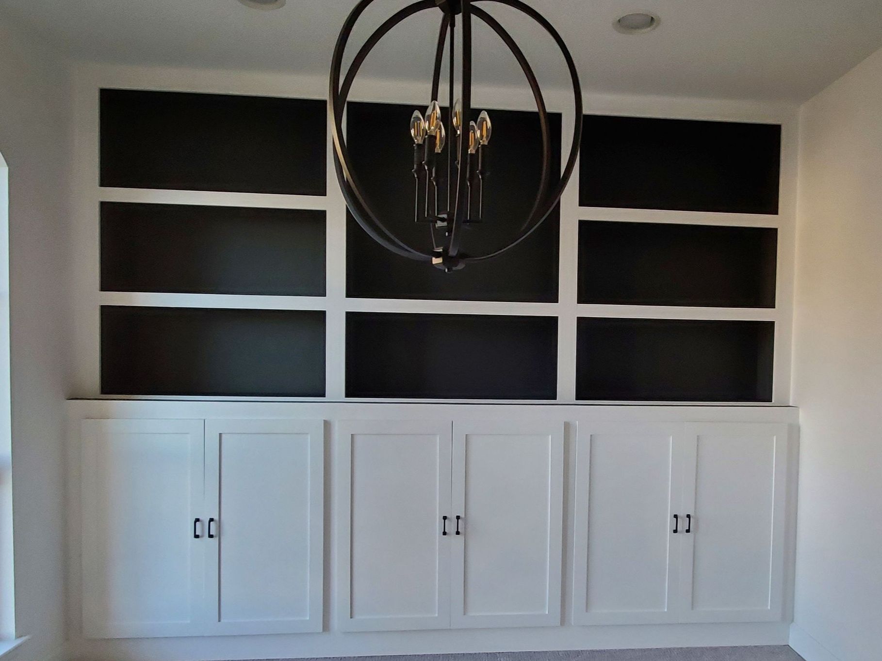 A chandelier hangs from the ceiling above a bookshelf