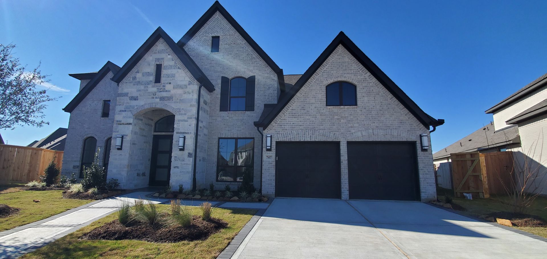 A large brick house with two garages and a concrete driveway
