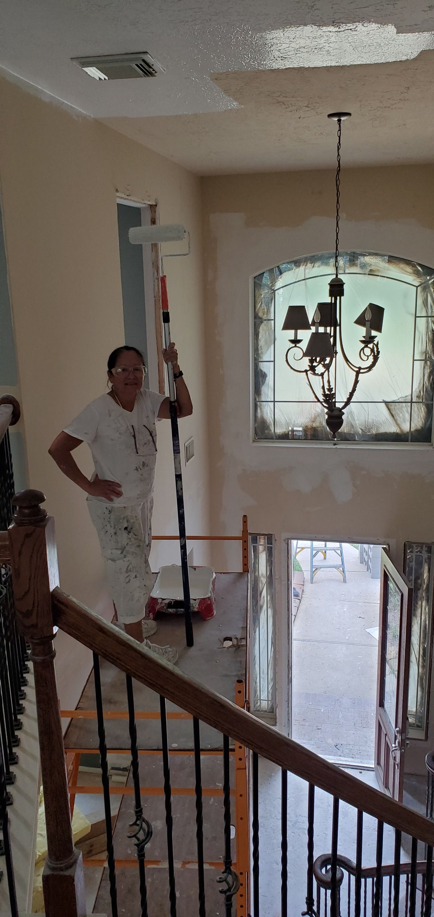 A man is standing on a ladder painting a wall.