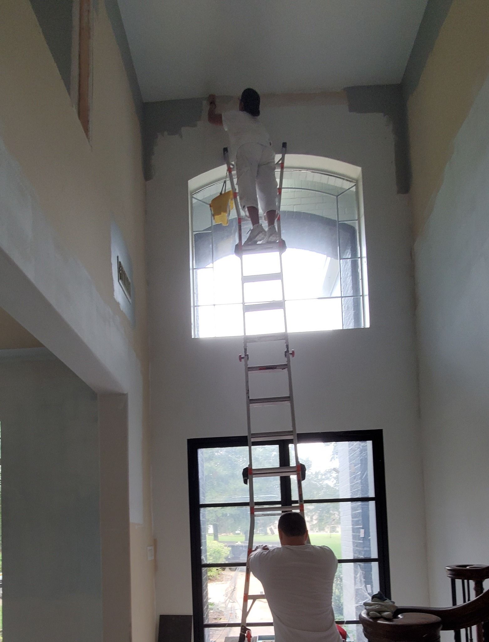 A man is standing on a ladder painting a wall.
