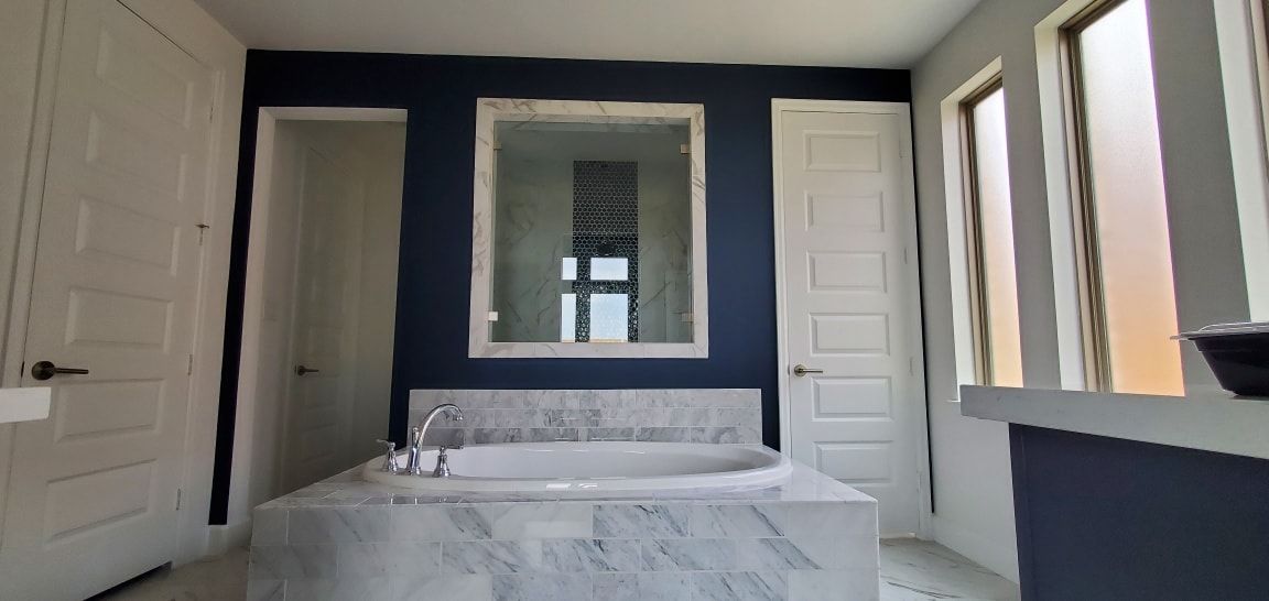 A bathroom with a bathtub , mirror , and blue walls.