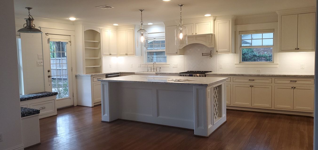 A kitchen with white cabinets and a large island in the middle.