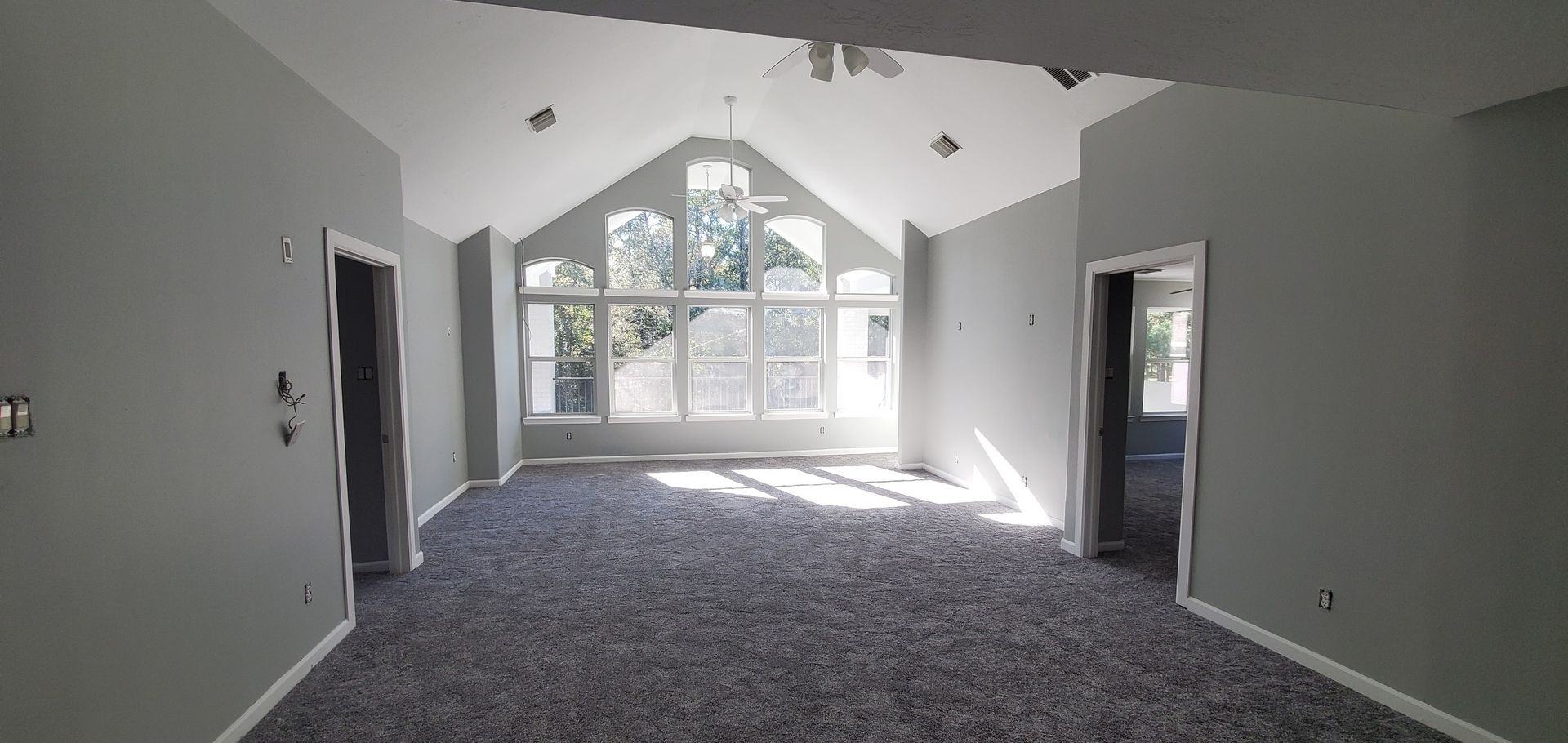 A large empty room with a vaulted ceiling and a lot of windows.