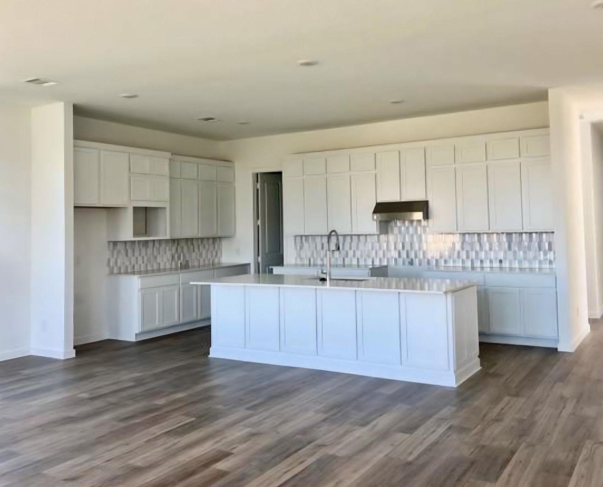 A kitchen with a lot of cabinets and appliances and a tiled floor.