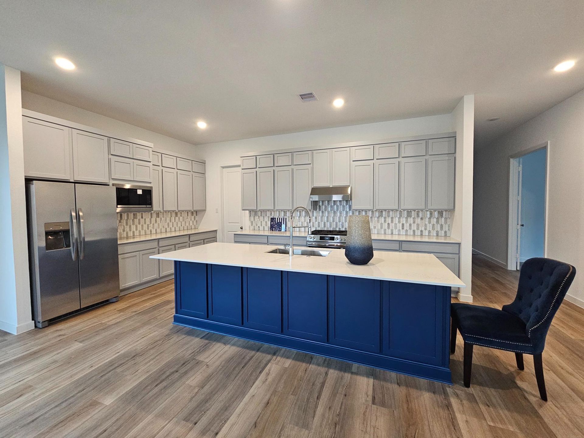 A kitchen with white cabinets , granite counter tops , stainless steel appliances , and a stool.