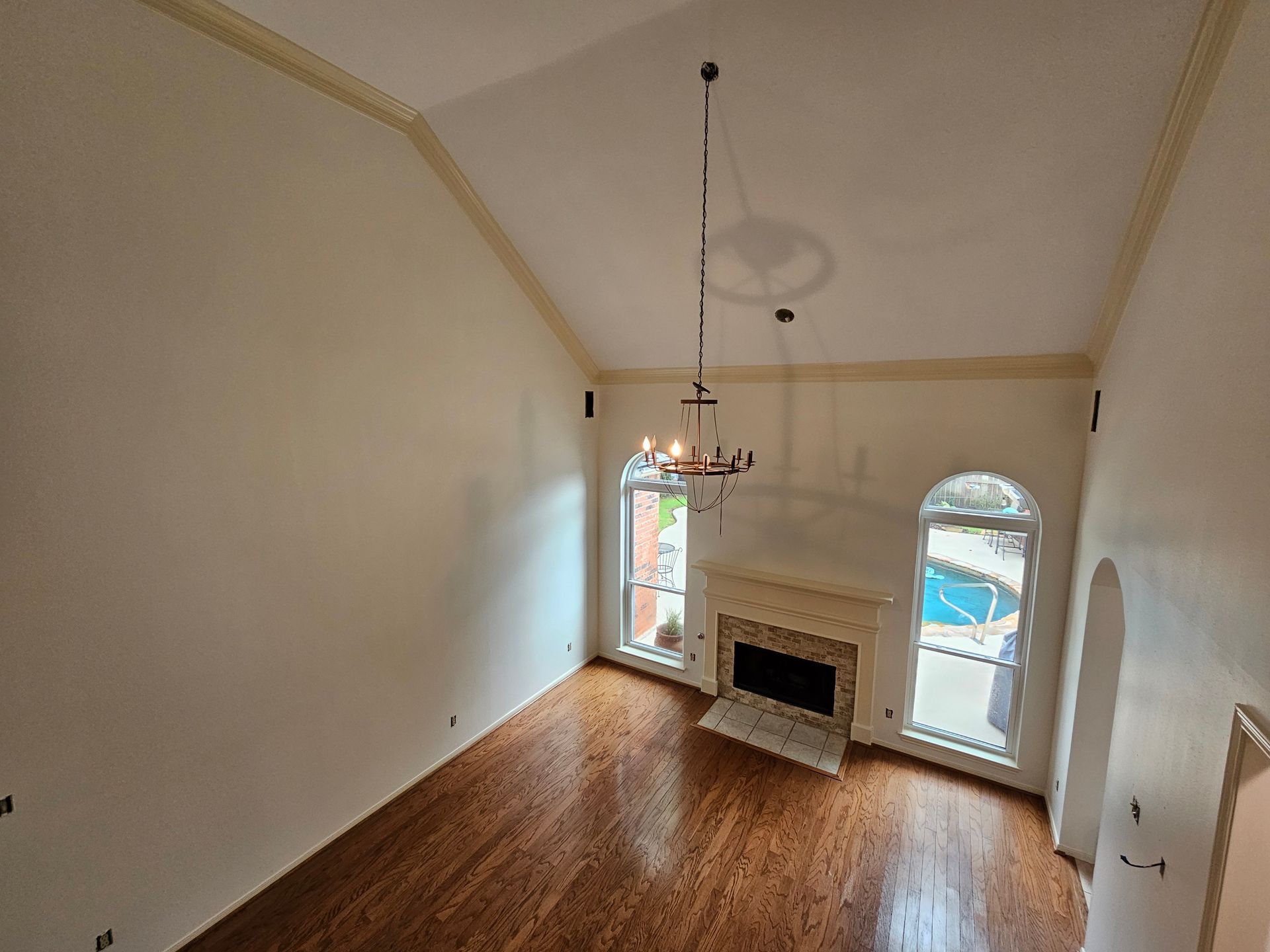 An empty living room with a ceiling fan and a window.