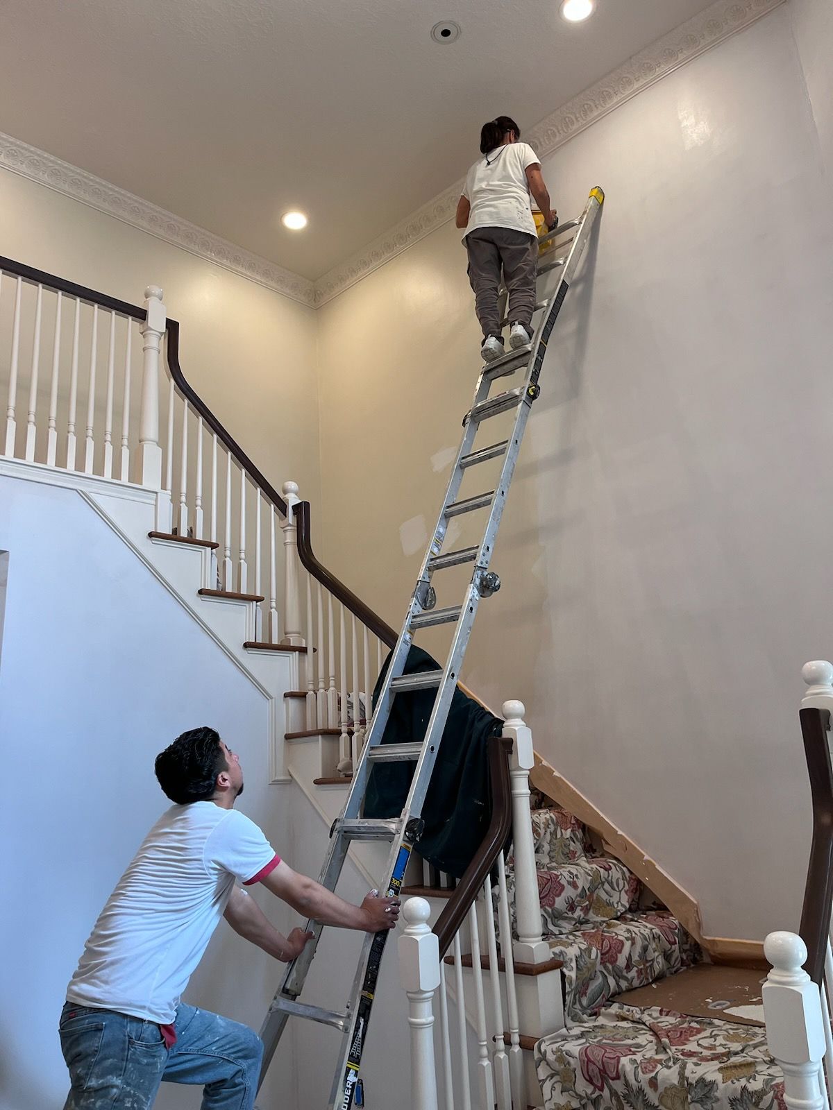 A man is climbing up a ladder to paint a wall.