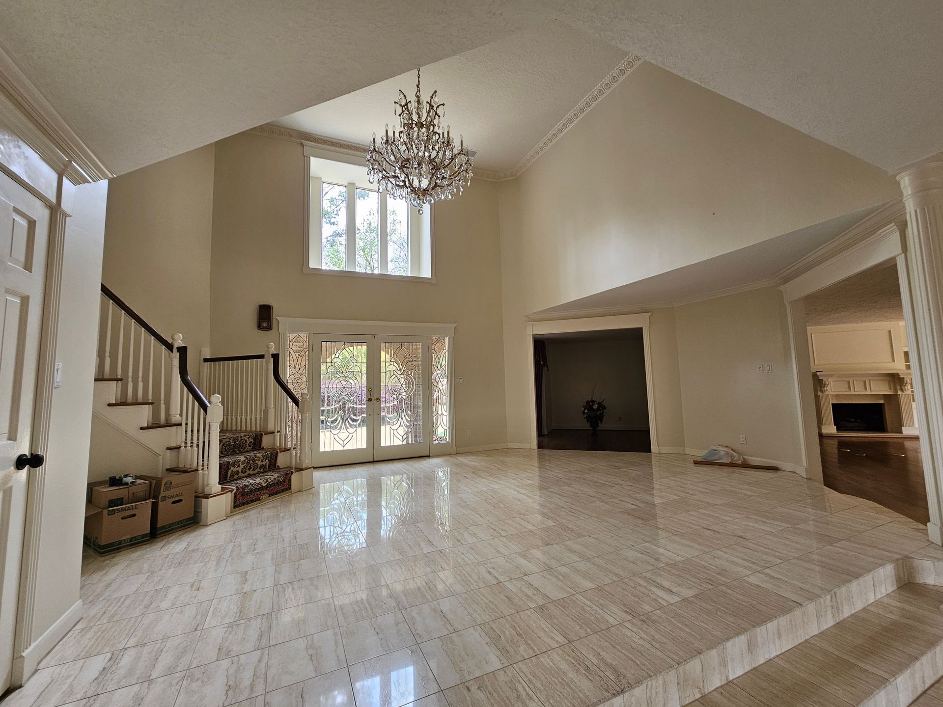 A large empty room with a chandelier and stairs.