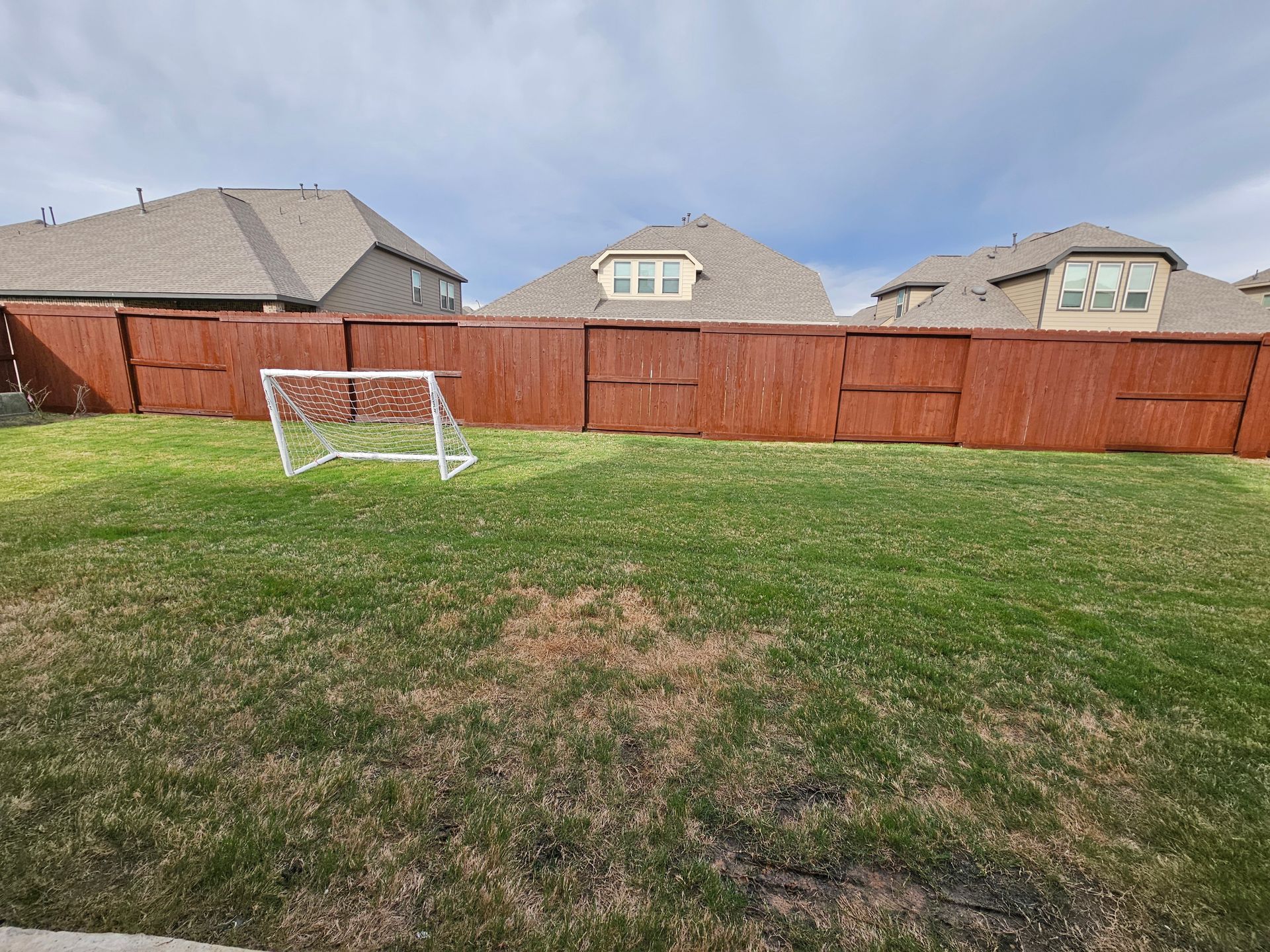 A backyard with a wooden fence and a soccer goal.