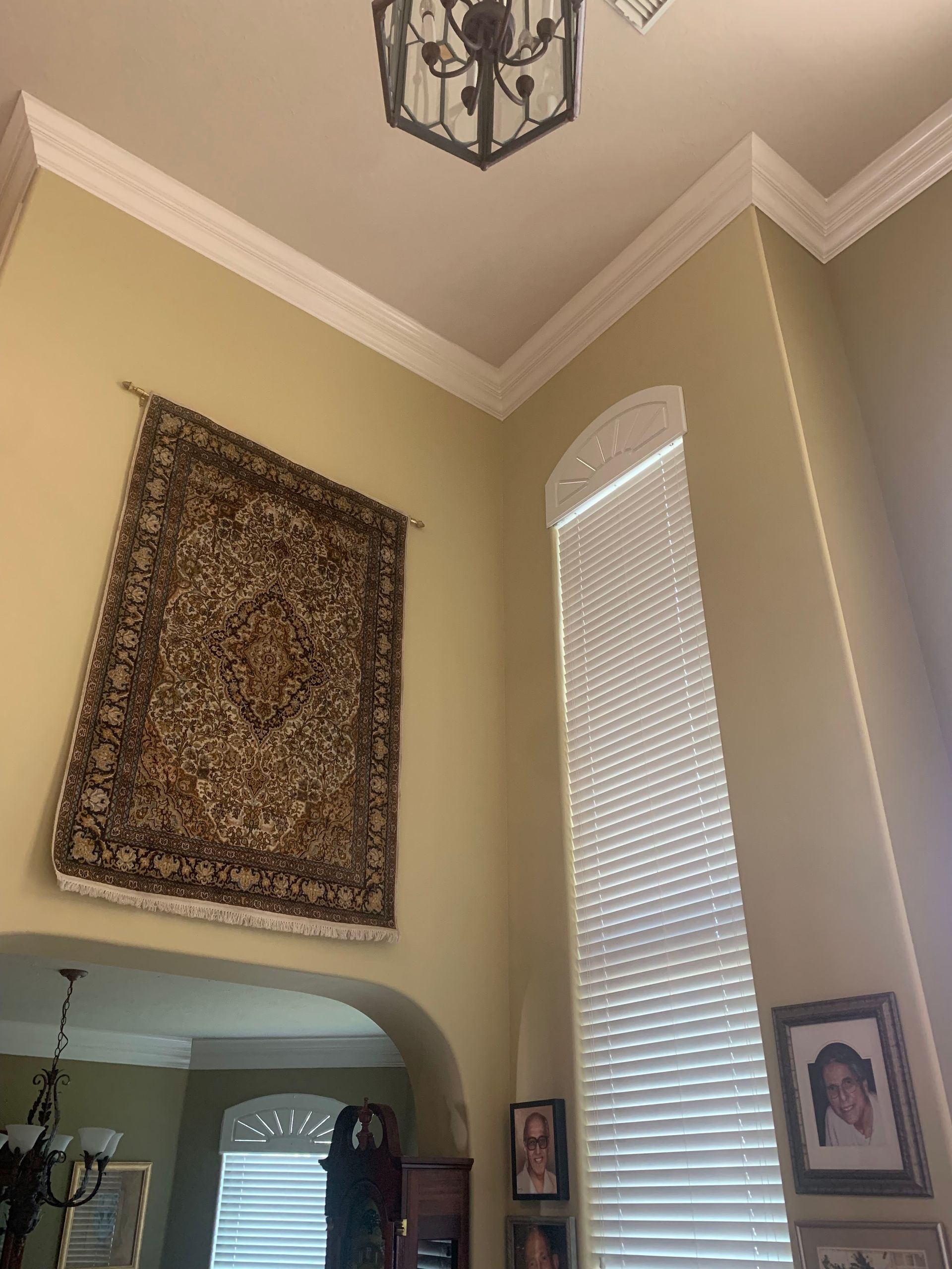 A living room with a rug hanging on the wall and a chandelier hanging from the ceiling.